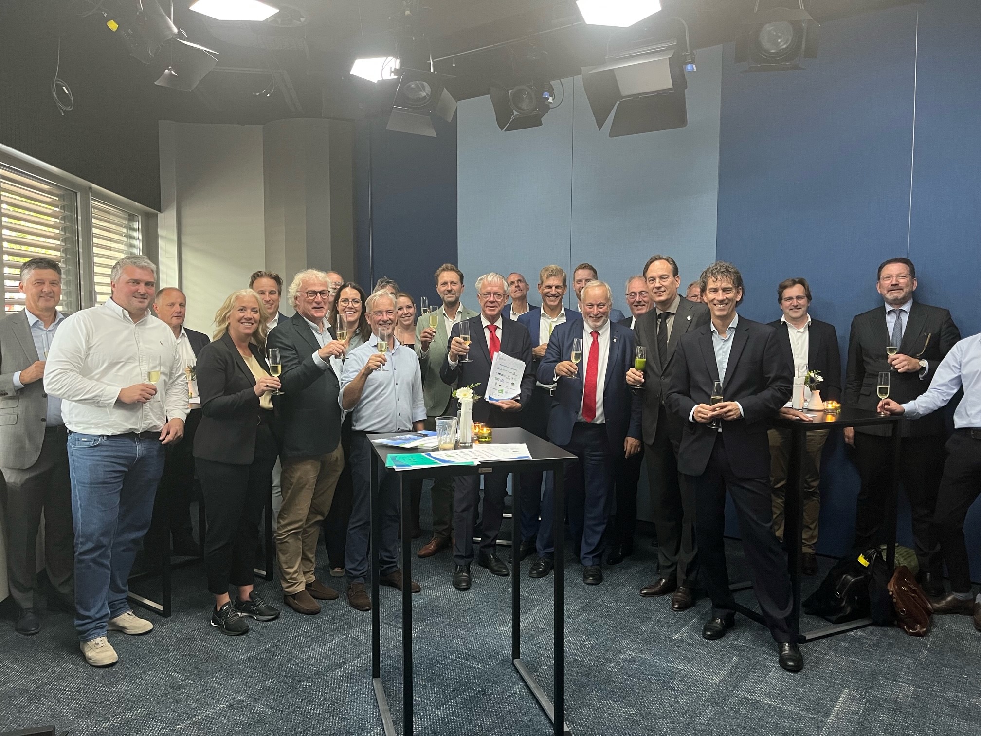 Alle ondertekenaars staan bij elkaar en heffen de champagneglazen.